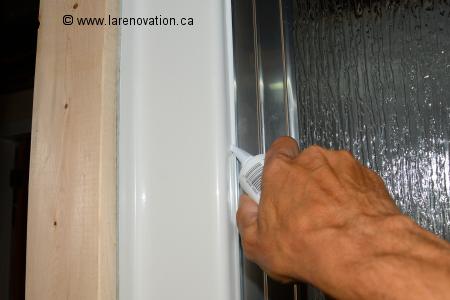 Photo de l'application du silicone le long de la porte de douche
